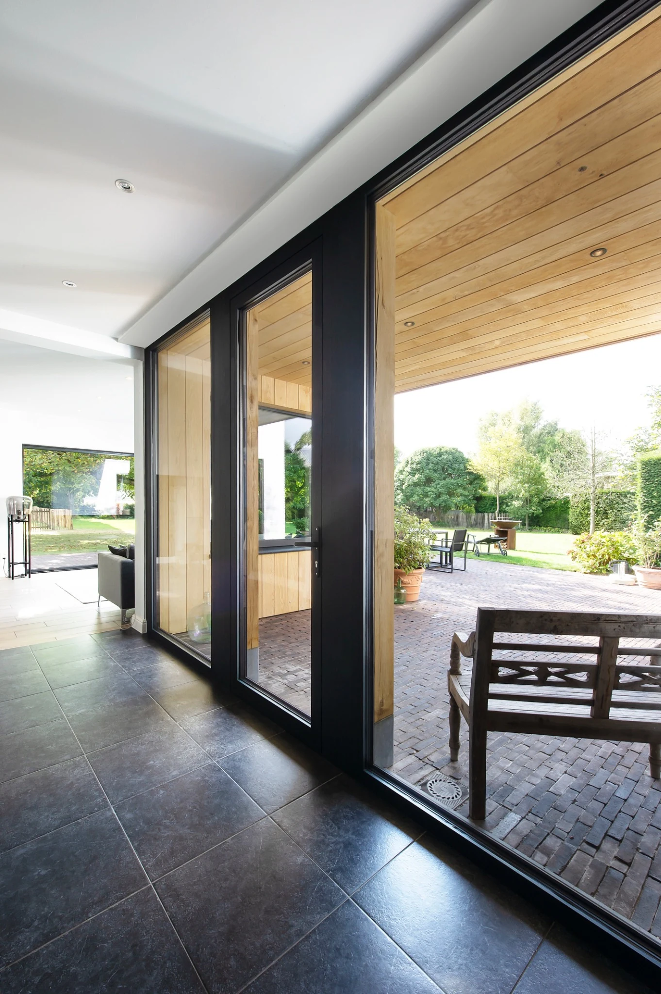 Moderne houten gevel met zwarte aluminium raamopening en zonwering
