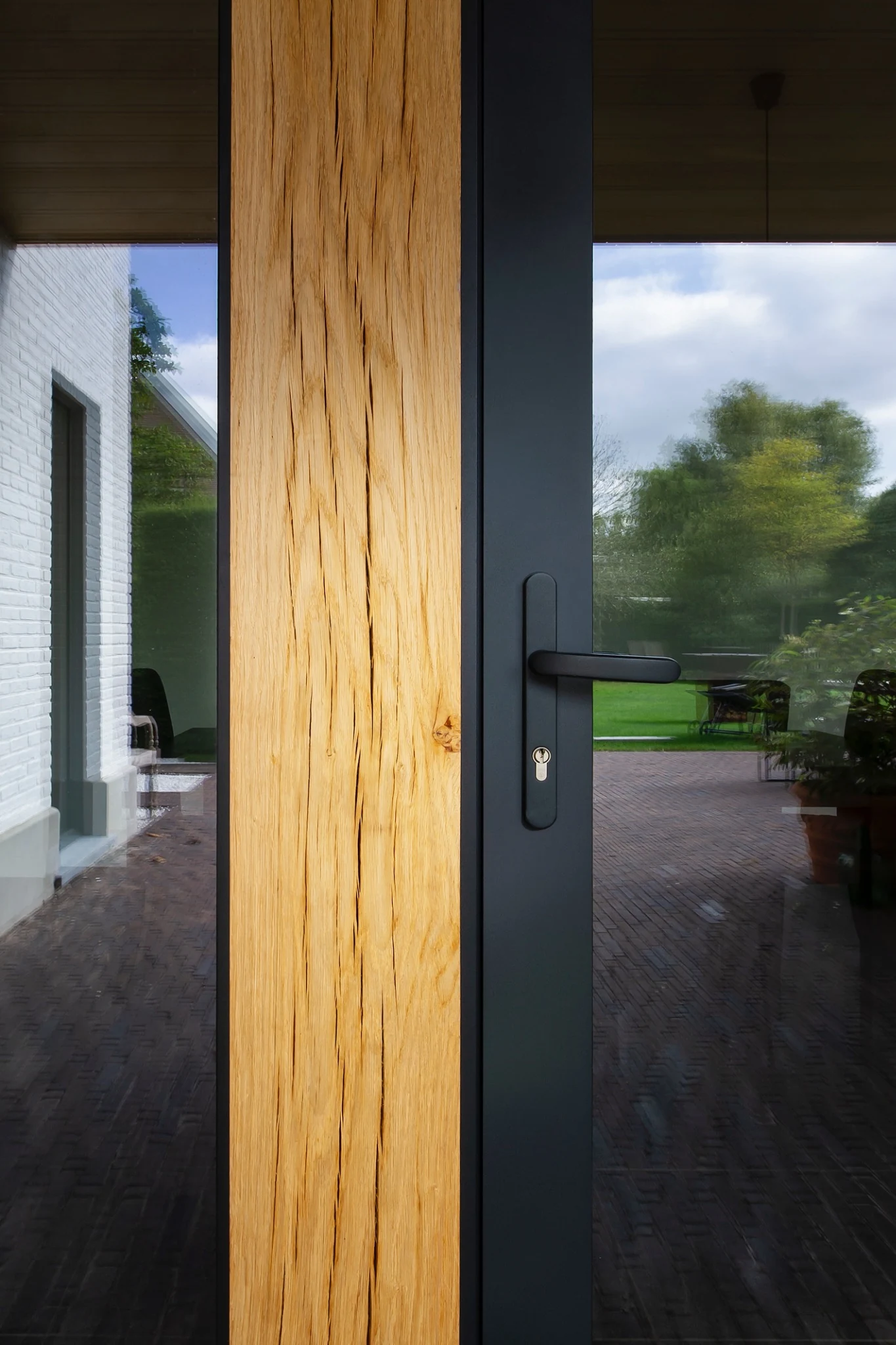 Detail van zwarte aluminium Holux-deur met houten gevelkolom